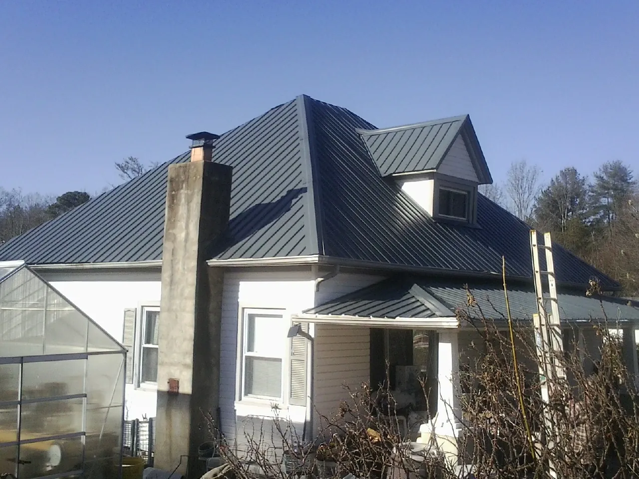 Dark blue standing seam metal roof on a white farmhouse with dormer — Slate & Tile Roof Repair by Roofing Brothers in Pulteney
