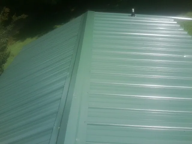 New green metal panels meeting at the ridge of a roof — Flat Roof Repair work by our crew in Pulteney