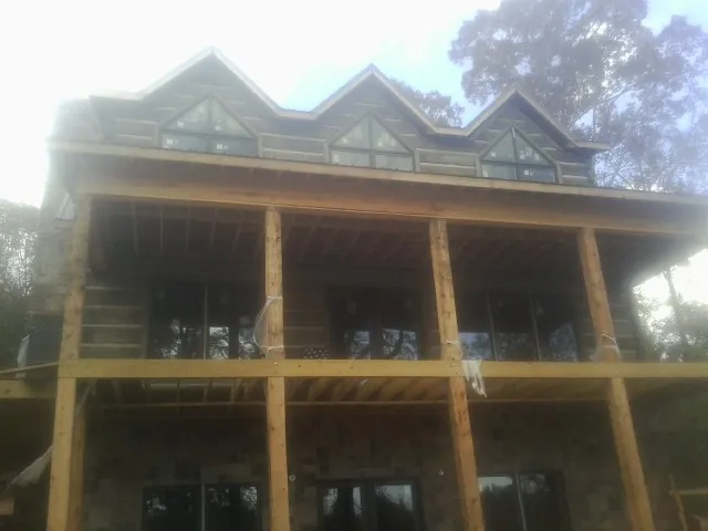 Dormers and porch framing on a large log home under construction — Roof Coating work by our crew in Pulteney