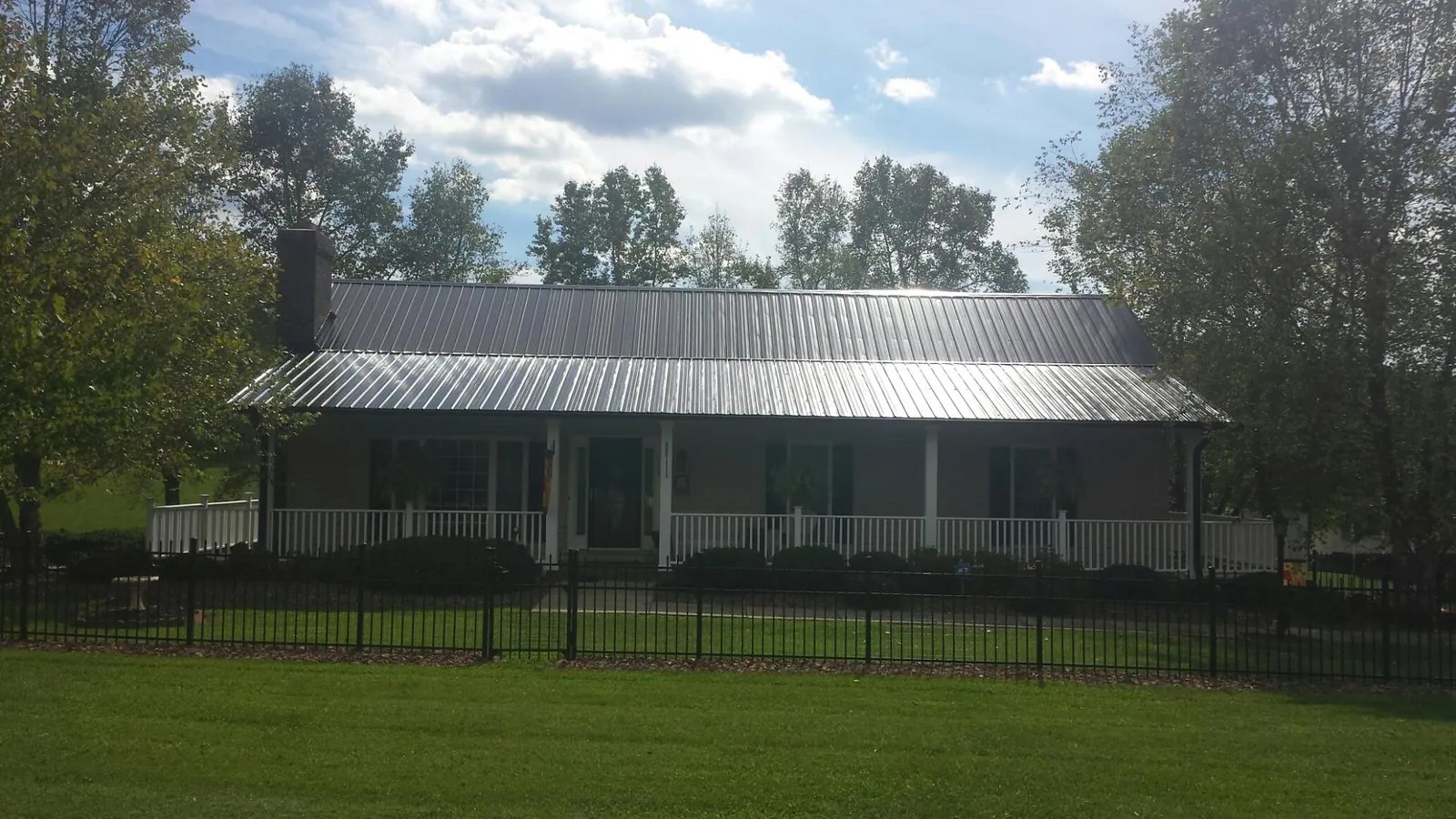 Gray metal roof on a brick ranch with a full width front porch — Gutter Guard Installation work by our crew in Pulteney