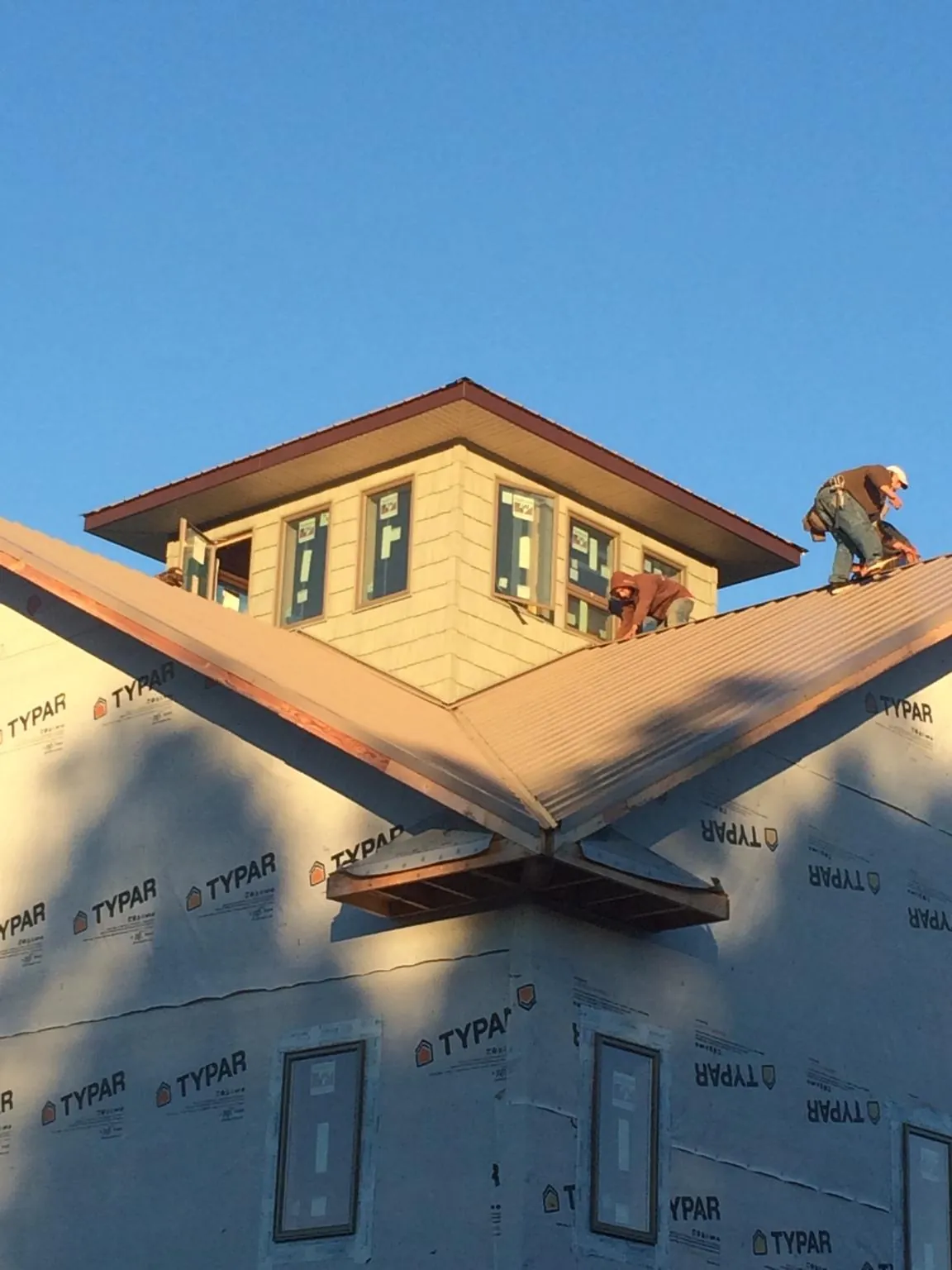 Roofers working around a rooftop cupola on a new metal roof at sunset — Roof Waterproofing in Pulteney by Roofing Brothers
